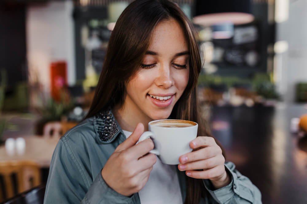 Young woman enjoying her cup of daily coffee for better health