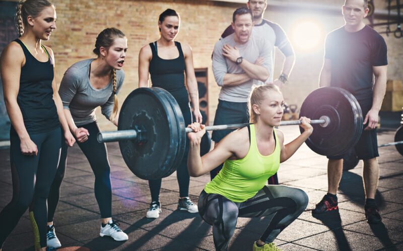 Woman squatting low with all her friends cheering