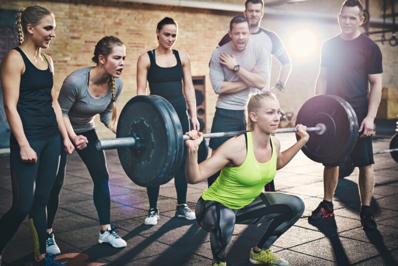 Woman squatting low with all her friends cheering