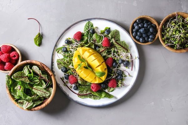 A plate with delicious salad and a cut mango