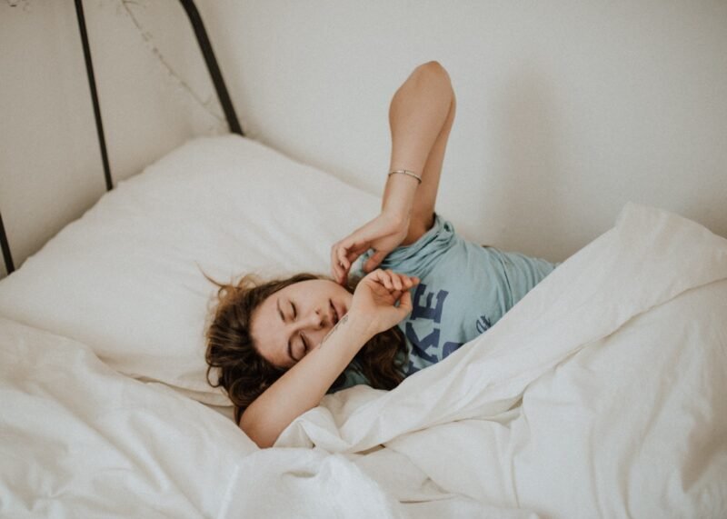 Woman in bed, slowly waking up with a stretch