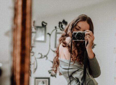 Woman taking a selfie in front of her mirror with a camera