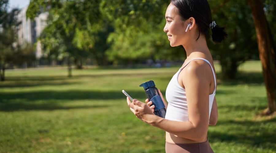 Woman walking in the park with headpones on and phone