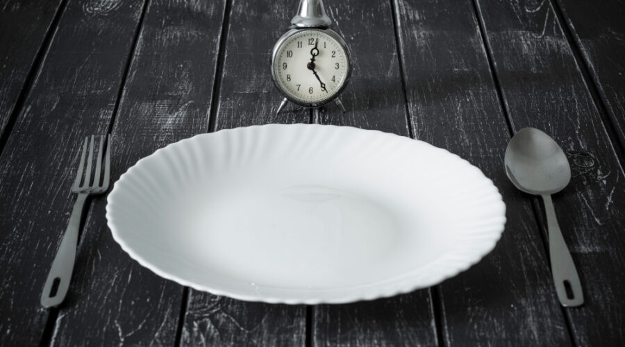 Clock and an empty plate with cutlery