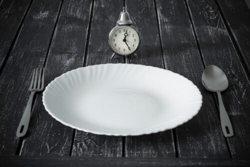 Clock and an empty plate with cutlery