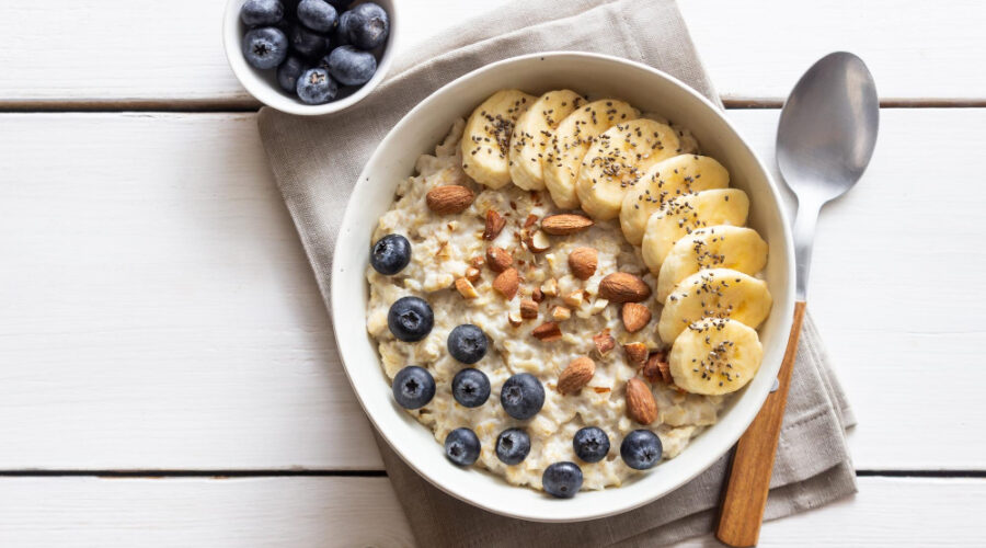 Delicious oatmeal breakfast with berries, green banana and nuts