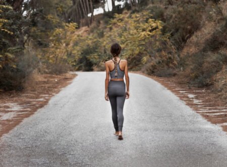A woman from behind walking on a road with her gym wear
