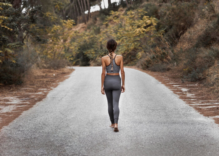 A woman from behind walking on a road with her gym wear