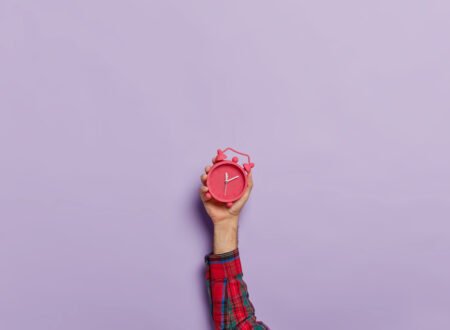 Person Holding up a red clock against purple background