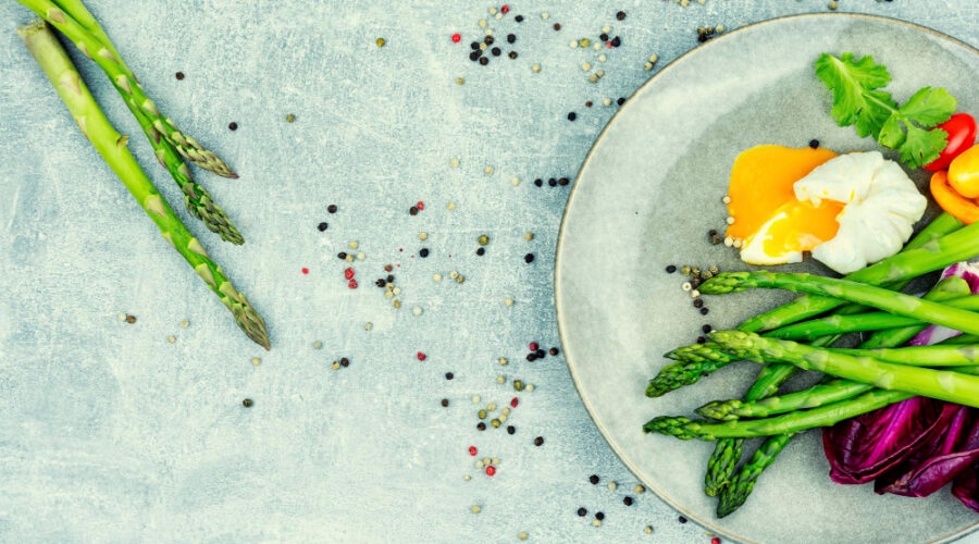 Asparagus on a white plate with eggs and other veggies