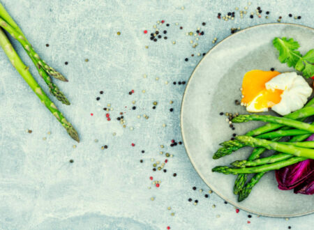 Asparagus on a white plate with eggs and other veggies