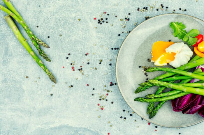 Asparagus on a white plate with eggs and other veggies