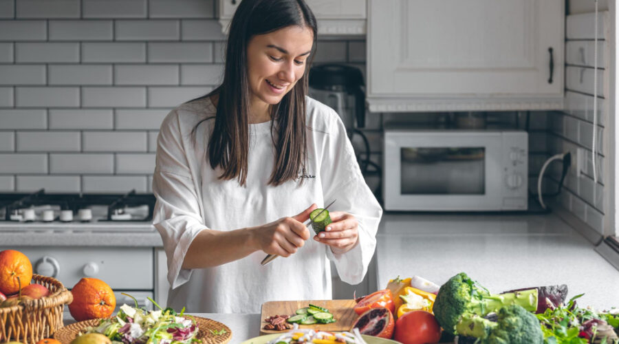 Woman in her kitchen cutting up cucumber for a healthy salad
