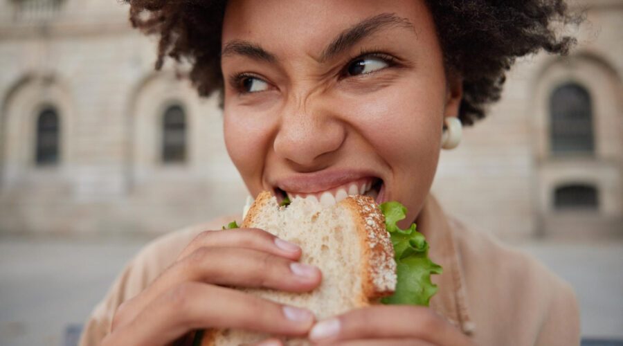 Woman hungry and taking a bite out of a delicious sandwich