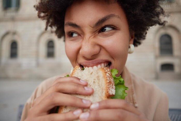 Woman hungry and taking a bite out of a delicious sandwich