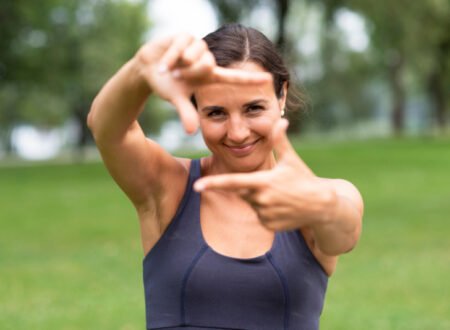 Fit woman with camera gesture in front of her face