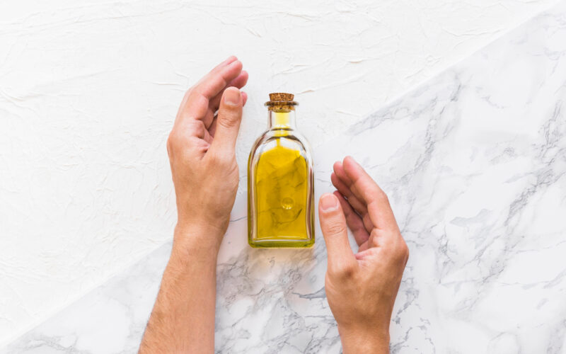Small bottle of oilve oil in between someones hands