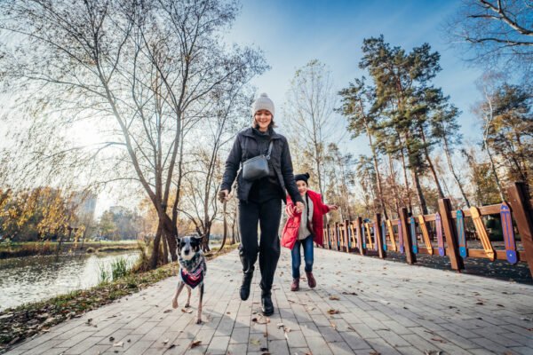 Woman walking with her dog and son in a park during autumn