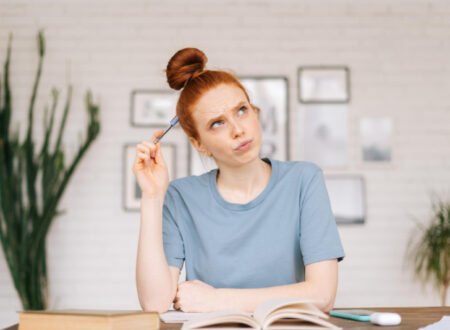 Redhead woman at home, studying and contemplating her material with a pencil directed to her brain