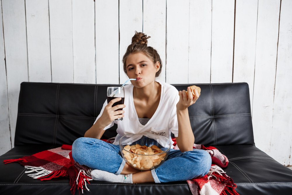 Woman on the couch eating some junk food