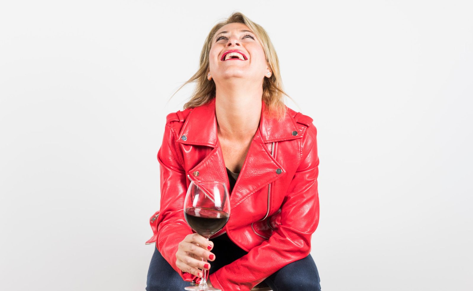 Woman-drinking-red-wine-with-a-red-leather-jacket-laughing