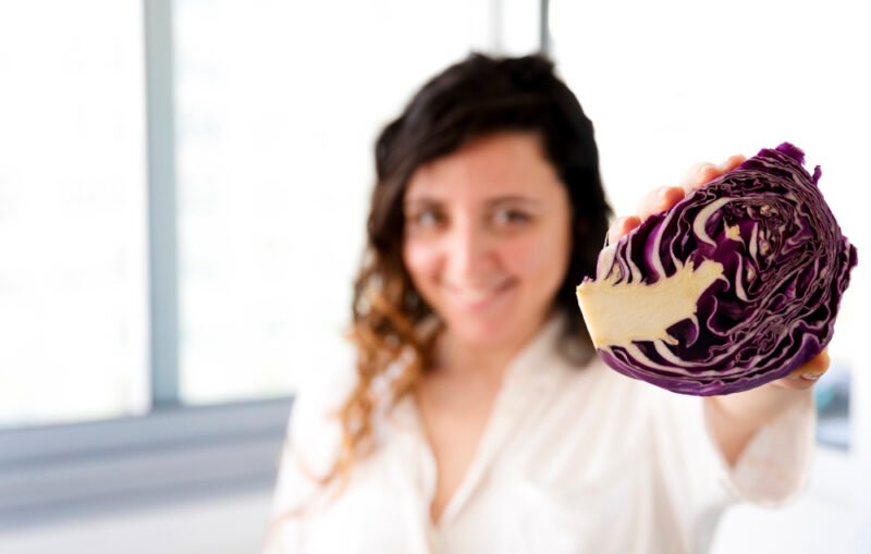 Woman holding half a red cabbage smiling