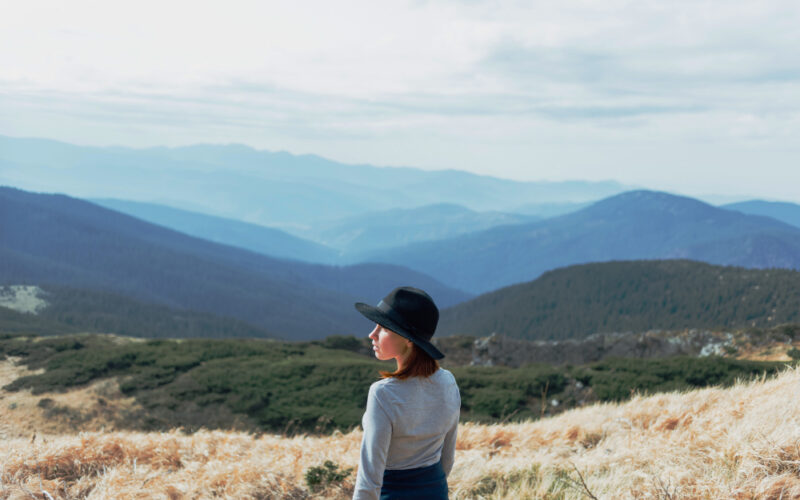 A girl posing on a hill, in front of a beautiful background
